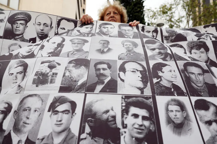 Manifestantes demonstram apoio à vítima de tortura da ditadura franquista em frente a um tribunal de Madri com imagens de mortos pelo regime