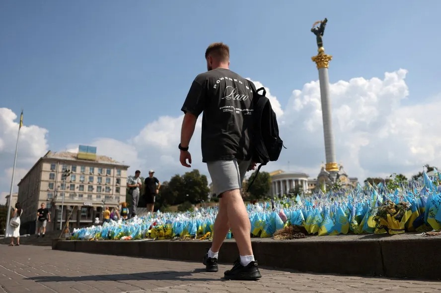 Homem passa por bandeiras ucranianas que homenageiam os soldados ucranianos mortos durante a guerra com a Rússia, em Kiev