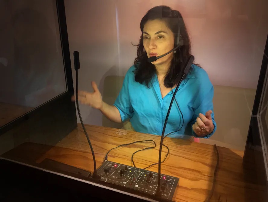 Graciela Pozzobon em cabine em audiodescrição 