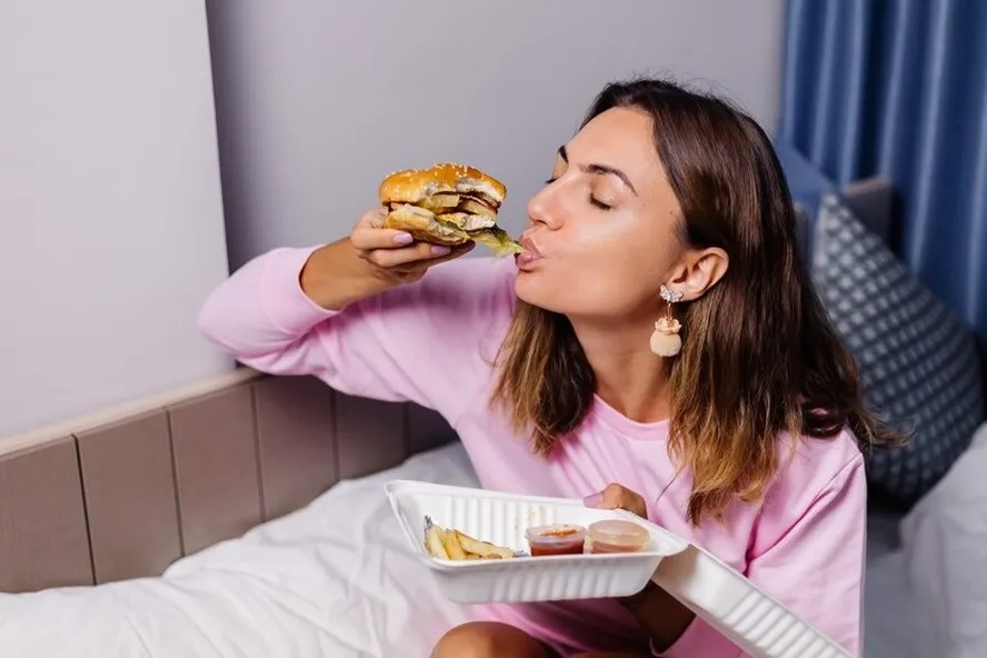 Mulher comendo hambúrguer: cientistas desvendam mistério da vontade de comer besteira