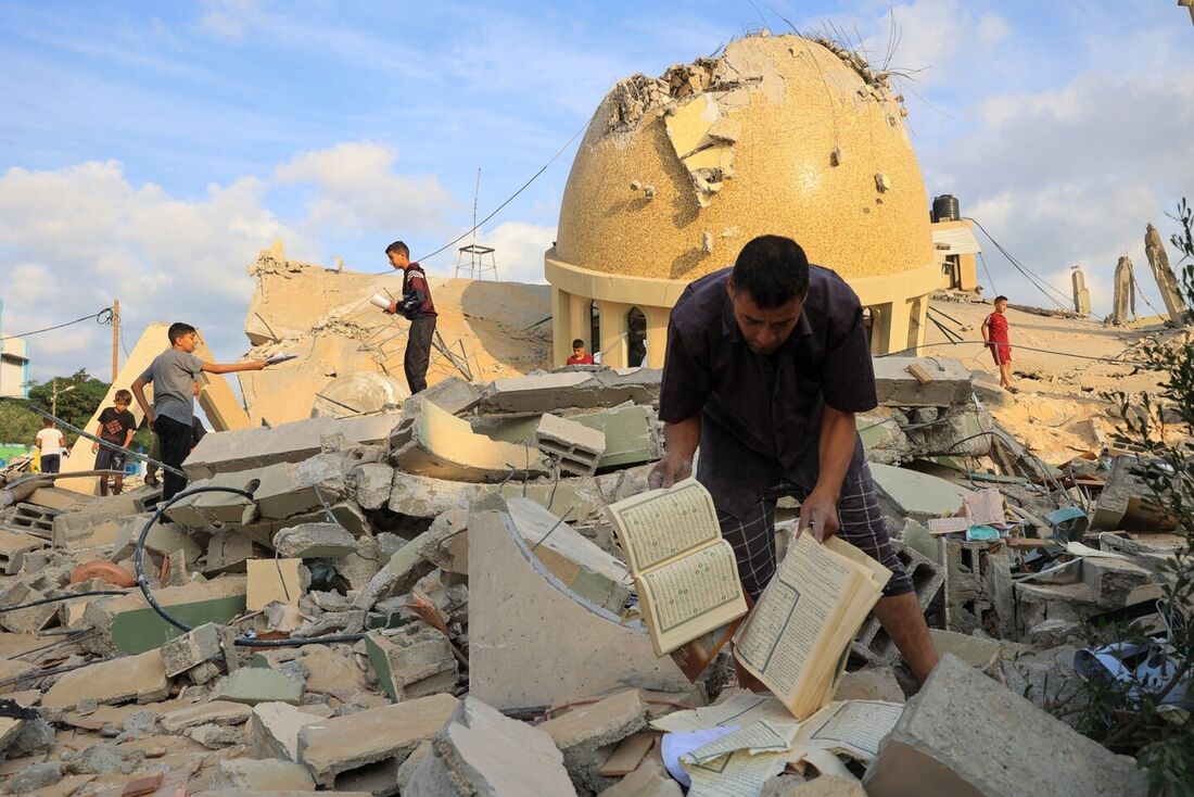 Pessoas examinam as ruínas de uma mesquita destruída em ataques aéreos israelenses em Khan Yunis, sul da Faixa de Gaza, em 8 de outubro de 2023