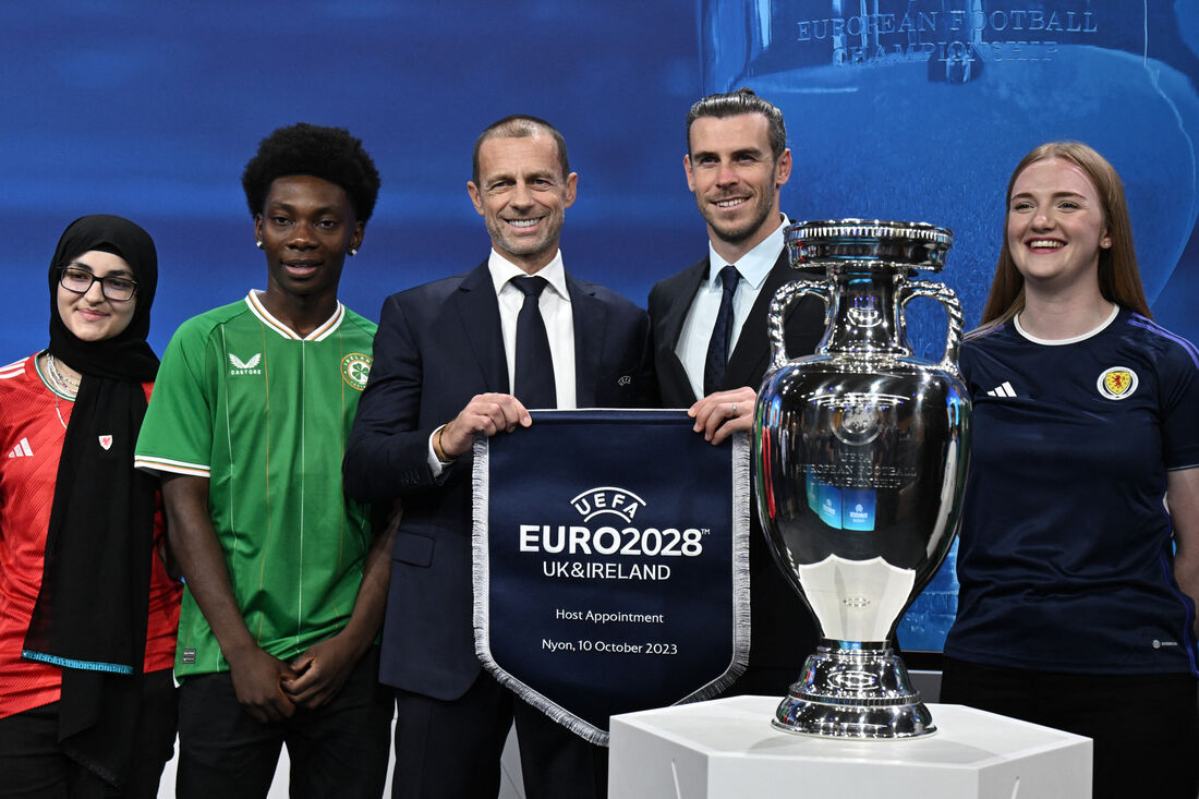 O jogador de futebol profissional galês aposentado, liderando a delegação do Reino Unido e da Irlanda, Gareth Bale, ao lado do pelo presidente da UEFA, Aleksander Ceferin, posa ao lado do troféu com os torcedores.