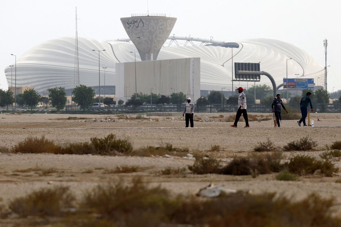 Homens jogando críquete em frente ao Janoub Stadium, que recebeu partidas da Copa do Mundo de 2022