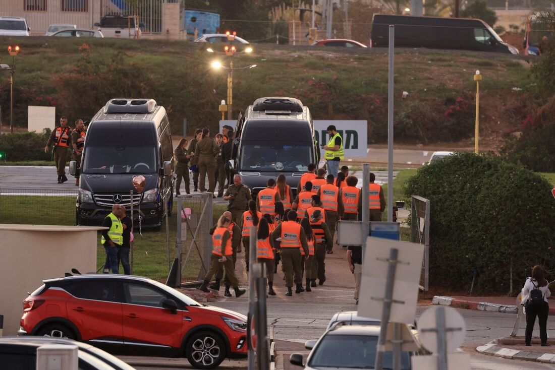 As forças de segurança israelenses estão ao lado dos ônibus que esperam no heliporto do centro médico Schneider de Tel Aviv, em 24 de novembro de 2023