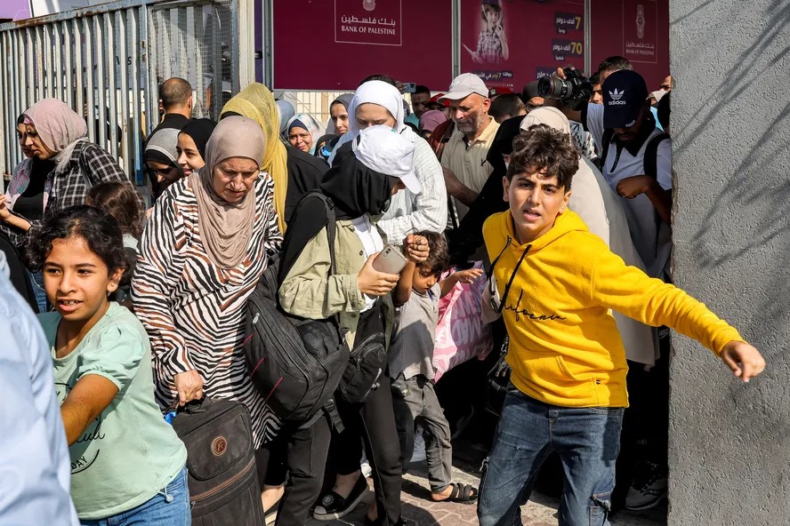 Pessoas atravessam um portão para entrar na passagem de fronteira de Rafah para o Egito, no sul da Faixa de Gaza 