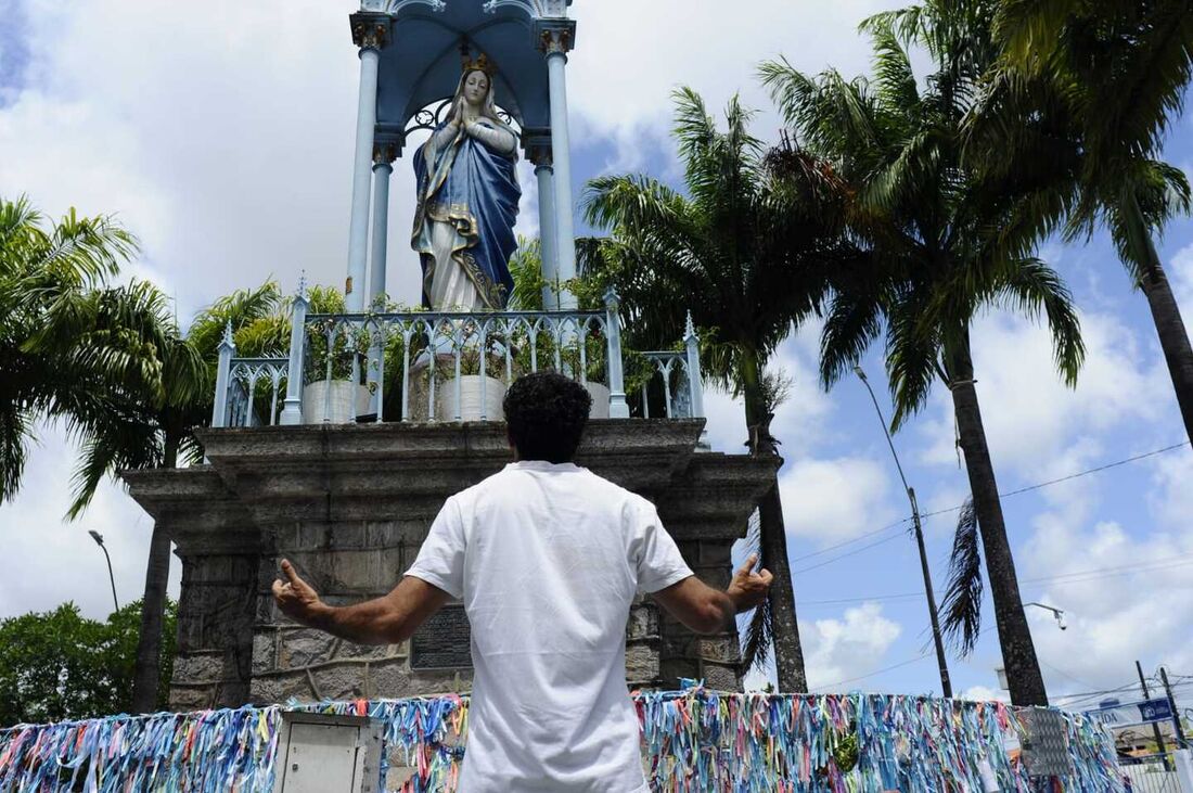 Homem reza aos pés da imagem de Nossa Senhora da Conceição