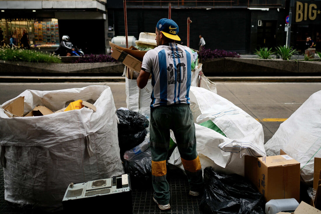  Catador vestindo a camisa de Messi procura por papelão em meio ao lixo na Avenida Corrientes, em Buenos Aires