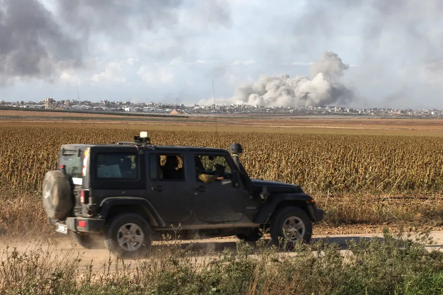 An Israeli military vehicle drives at the border with the Gaza Strip on December 9, 2023, as smoke billows in the Palestinian territory amid ongoing battles with the militant group Hamas 