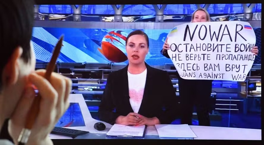 Mulher acompanha jornal do canal Russian Chanel, pela tela de computador