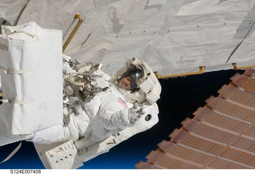 Astronauta acena para câmera posicionada no interior da Estação Espacial Internacional 