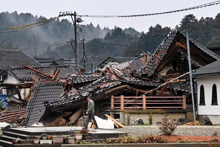 Homem caminha pelos escombros de casa destruída pelo terremoto no Japão