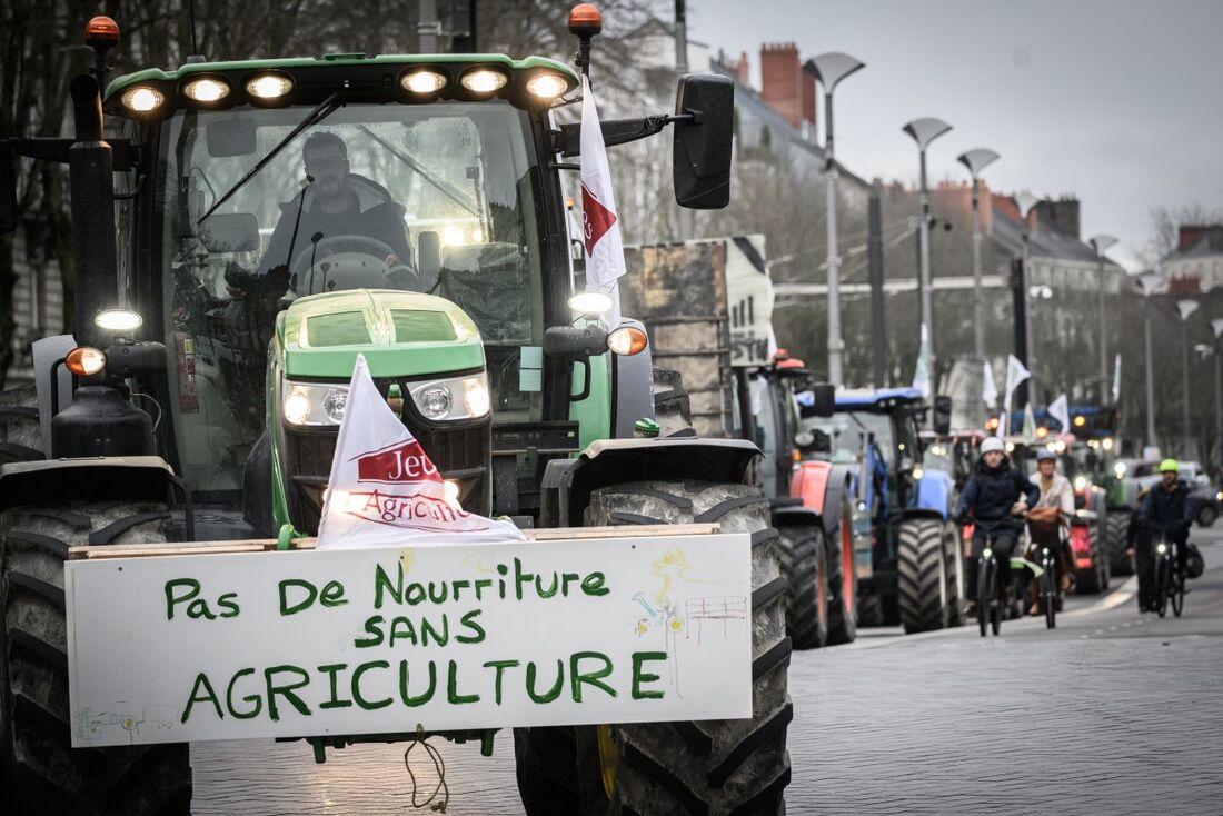 Agricultor conduz trator com um cartaz que diz "não há comida sem agricultura" durante um comício no centro de Nantes 