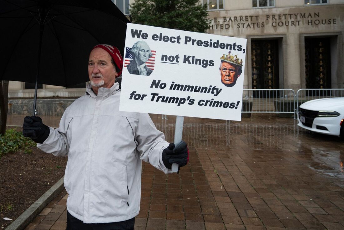 Manifestante em frente ao tribunal durante julgamento da imunidade criminal do ex-presidente Donald Trump