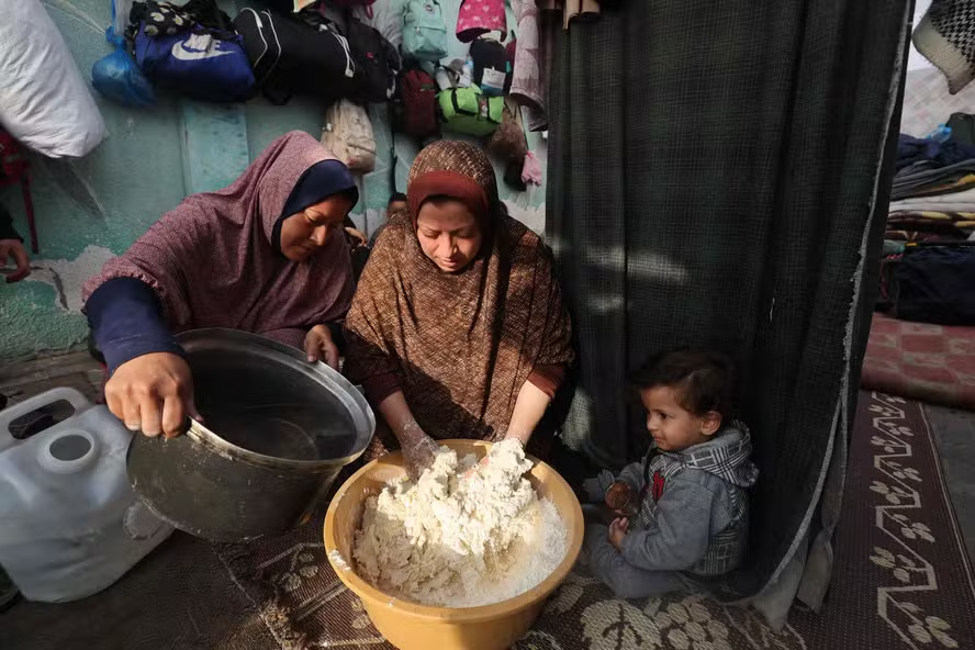 Mulheres palestinas preparam pão dentro de uma tenda em Rafah, no sul da Faixa de Gaza