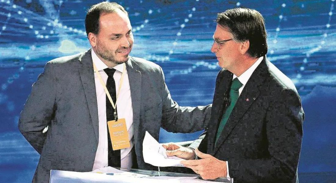 Carlos ao lado do pai, o então presidente Jair Bolsonaro, durante debate nas eleições de 2022