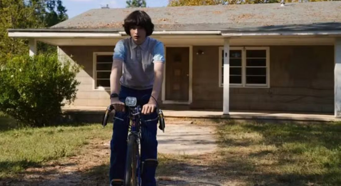 Cena de 'Stranger Things' com a casa dos Byers ao fundo