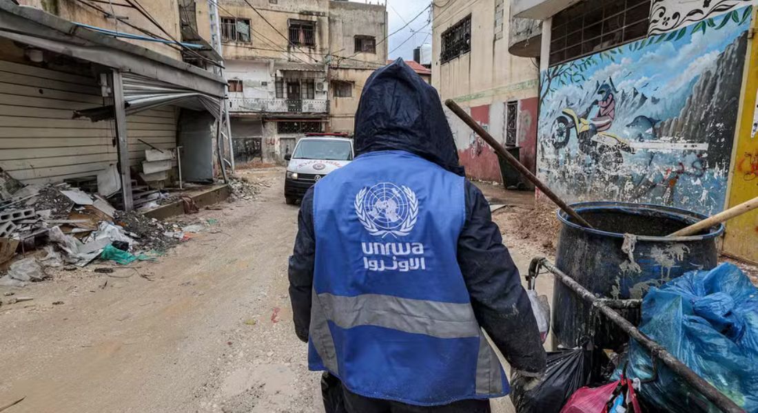 Catador de lixo veste casaco com logo da UNRWA em Jenin