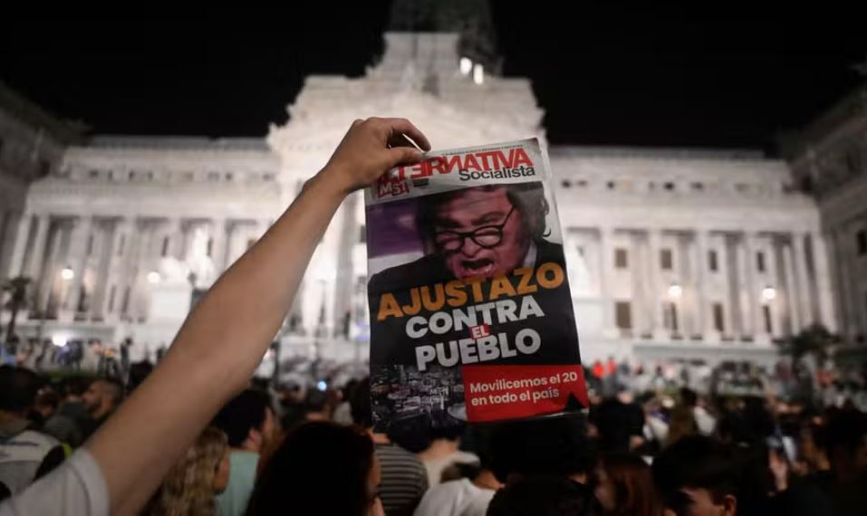 Manifestante segura panfleto com foto de Milei durante protesto contra o presidente