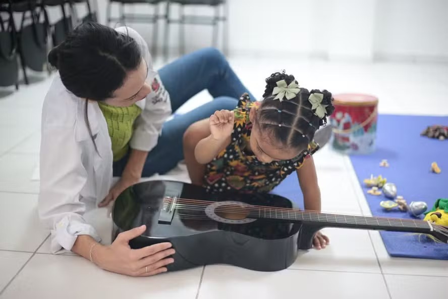 Fonoaudióloga e musicoterapeuta Vanessa Lira Vieira em uma sessão de musicoterapia com uma pequena paciente 