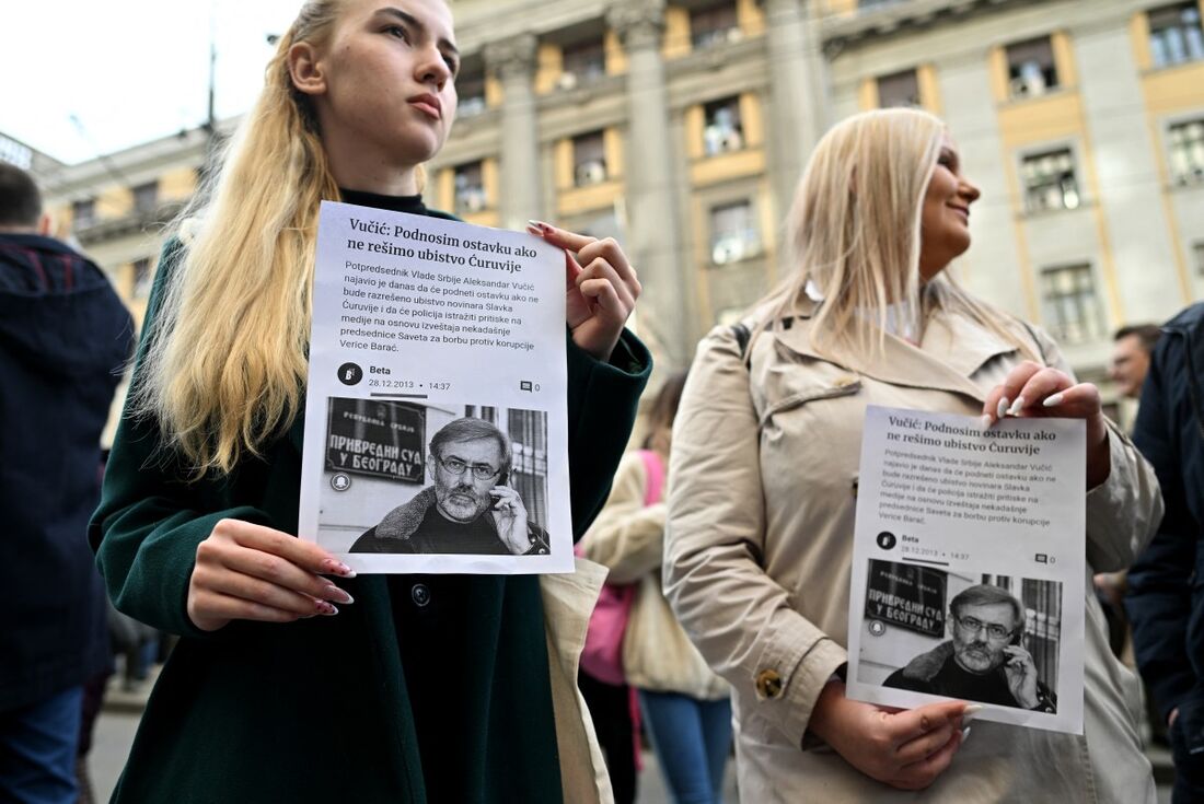 Manifestantes seguram retratos do jornalista Slavko Curuvija, reunidos em Belgrado, em 5 de fevereiro de 2024