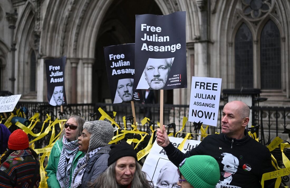 Manifestantes seguram cartazes enquanto protestam do lado de fora do Royal Courts of Justice, o Tribunal Superior da Grã-Bretanha, no centro de Londres