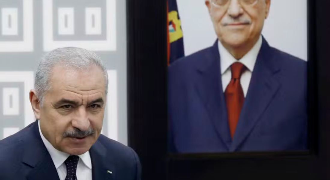 O primeiro-ministro palestino, Mohammad Shtayyeh, ao lado de um retrato do presidente da Autoridade Nacional Palestina, Mahmud Abbas