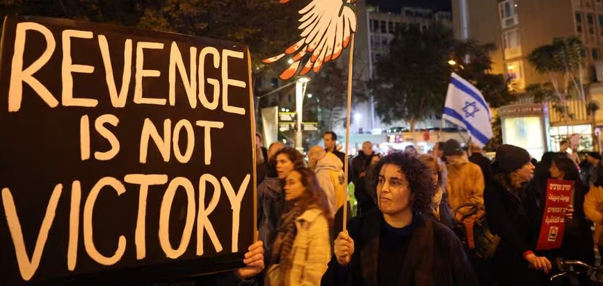 Ativistas erguem cartazes e faixas enquanto se manifestam contra a guerra em Gaza em frente ao Ministério da Defesa em Tel Aviv