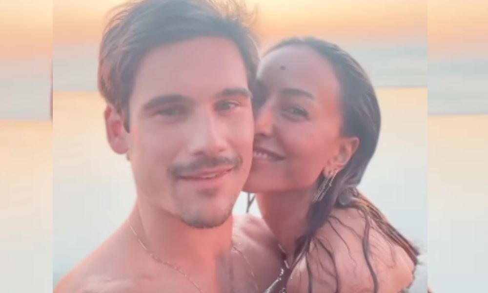 O casal abraçado em uma piscina de borda infinita com vista para o mar