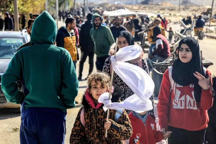 Menina segura bandeira branca enquanto caminha com outros palestinos deslocados de Khan Younis 