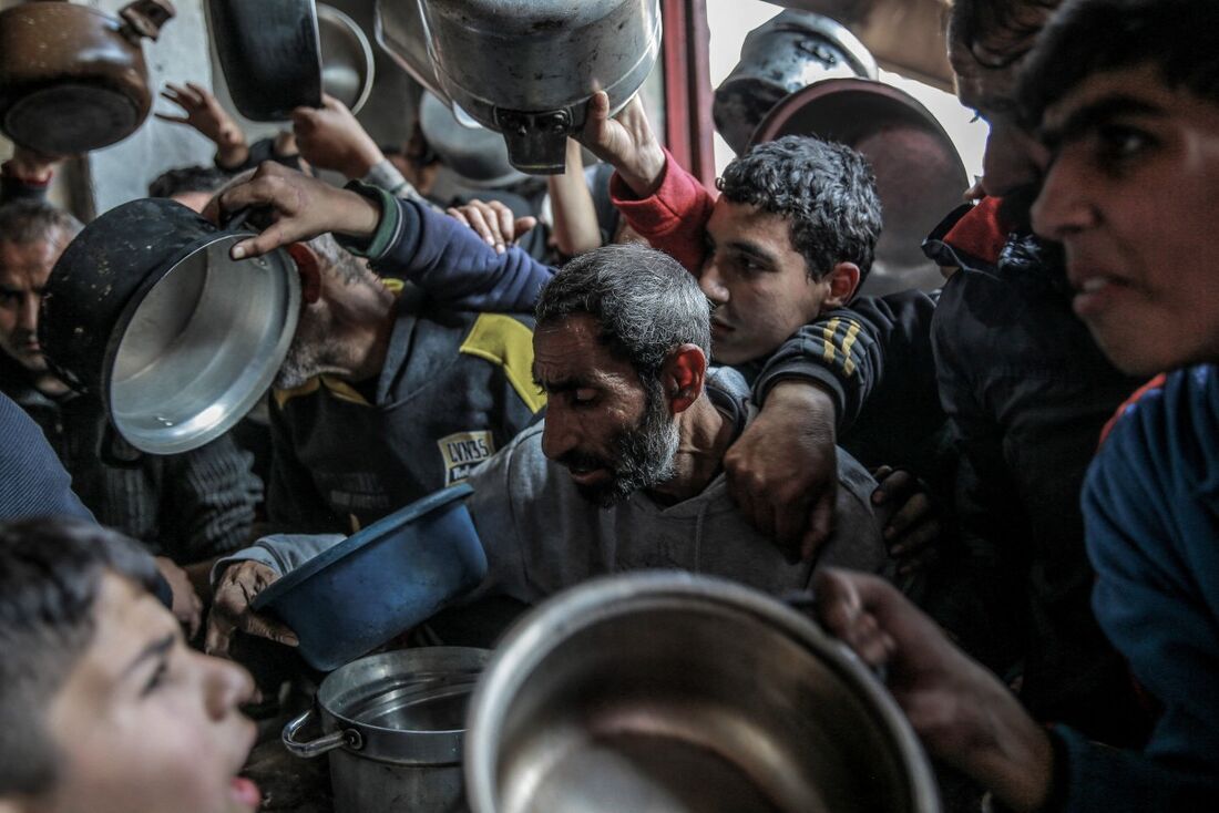 Palestinos se reúnem para coletar alimentos humanitários em Beit Lahia, no norte da Faixa de Gaza,