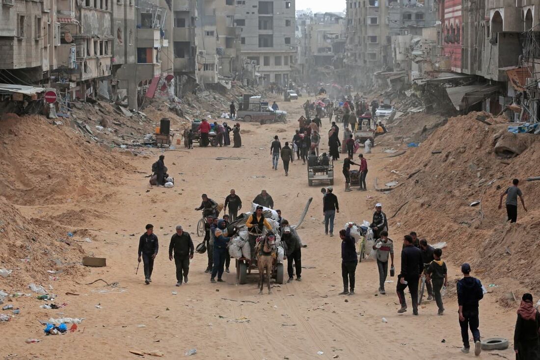 Palestinos carregam seus pertences por uma rua em Khan Yunis, no sul da Faixa de Gaza