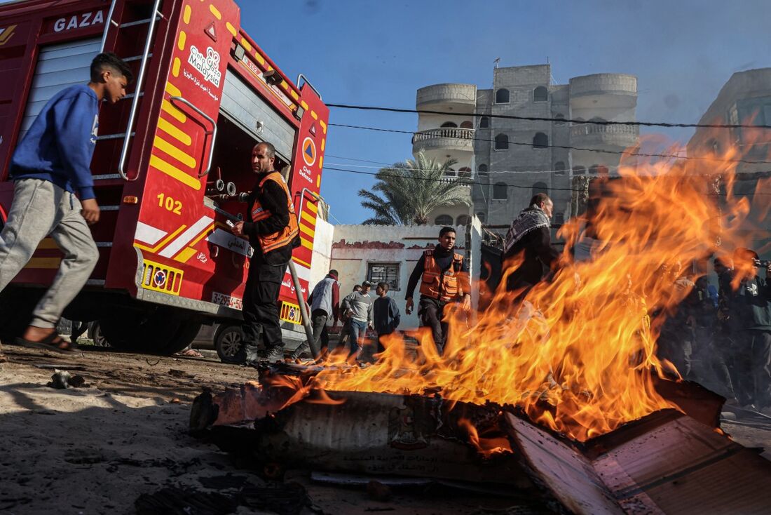 Membros da Defesa Civil Palestina apagam um carro em chamas após o bombardeio israelense em Rafah