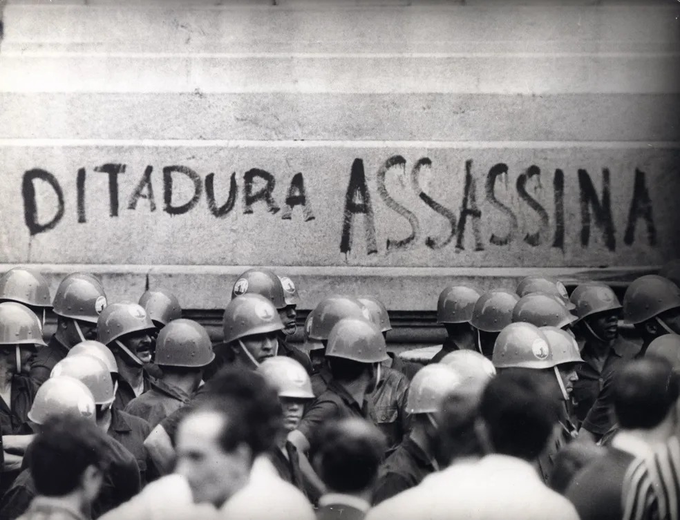 Policiais militares vigiam protesto de estudantes no Centro do Rio de Janeiro contra a ditadura militar e passam por pichação com os dizeres 'Ditadura assassina', em 1&ordm; de abril de 1968 