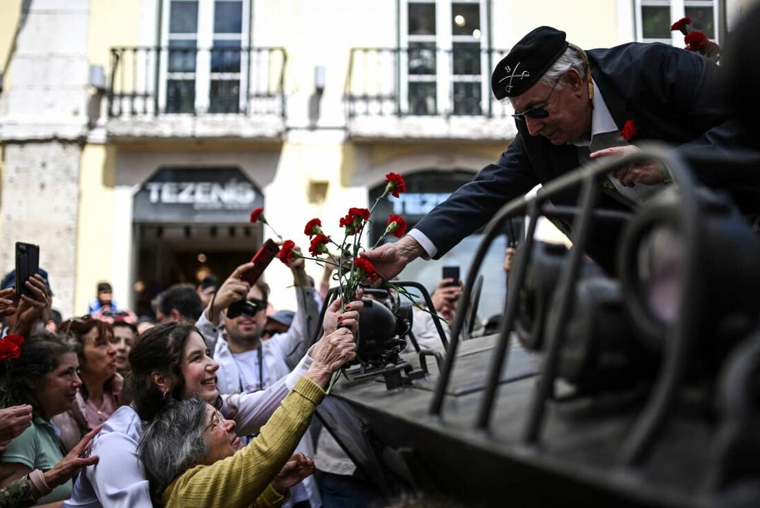 Celeste Caeiro, de 90 anos (à direita), oferece um buquê de cravos a um ex-soldado durante um desfile militar para celebrar o 50&ordm; aniversário da Revolução dos Cravos em Lisboa, em 25 de abril de 2024.