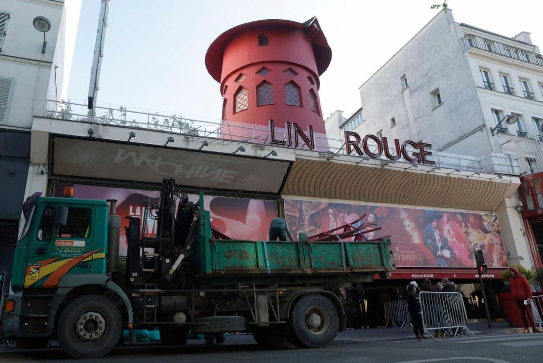 Trabalhadores carregam as pás do moinho de vento do Moulin Rouge, que desabou durante a noite sem causar ferimentos, disseram os bombeiros à AFP, em Paris, em 25 de abril de 2024.