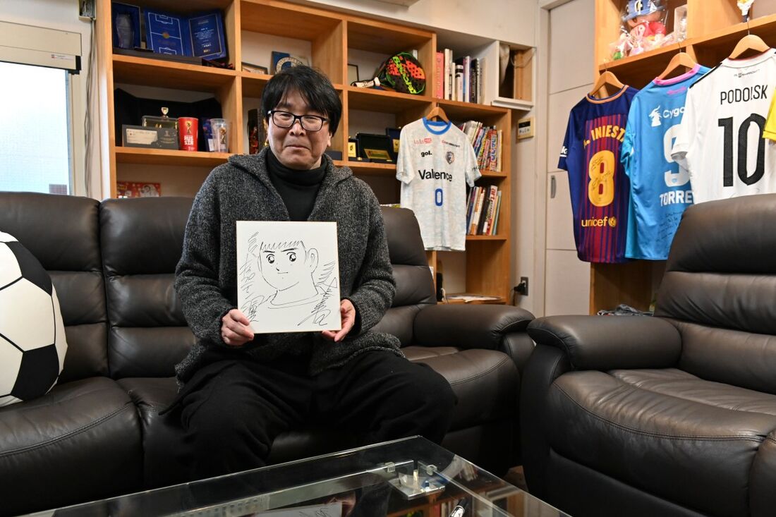 Yoichi Takahashi, mais conhecido por sua obra "Captain Tsubasa", exibindo seu autógrafo com a pintura do personagem principal