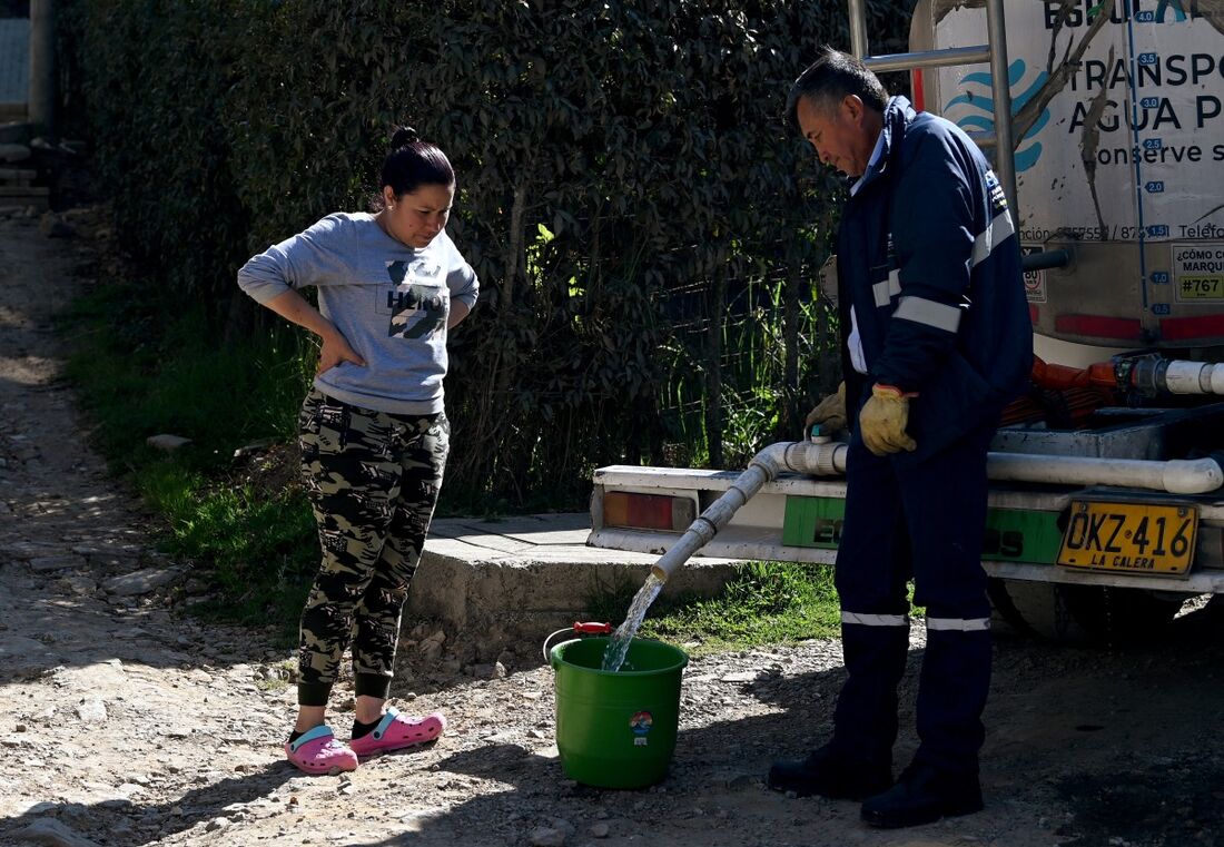 Uma mulher coleta água potável de um caminhão-pipa em La Calera, perto de Bogotá