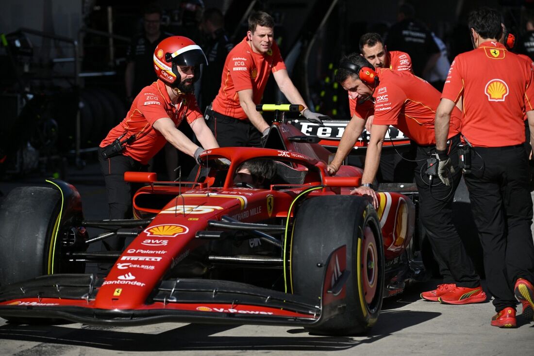 Os mecânicos empurram o carro do piloto espanhol da Ferrari, Carlos Sainz