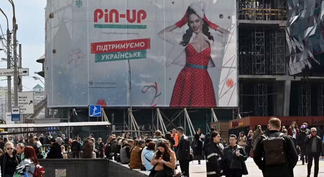 Ucranianos caminham diante de outdoor com propaganda de um cassino online em Kiev; jogos de azar foram proibidos para o Exército da Ucrânia após indícios de que soldados estão viciados