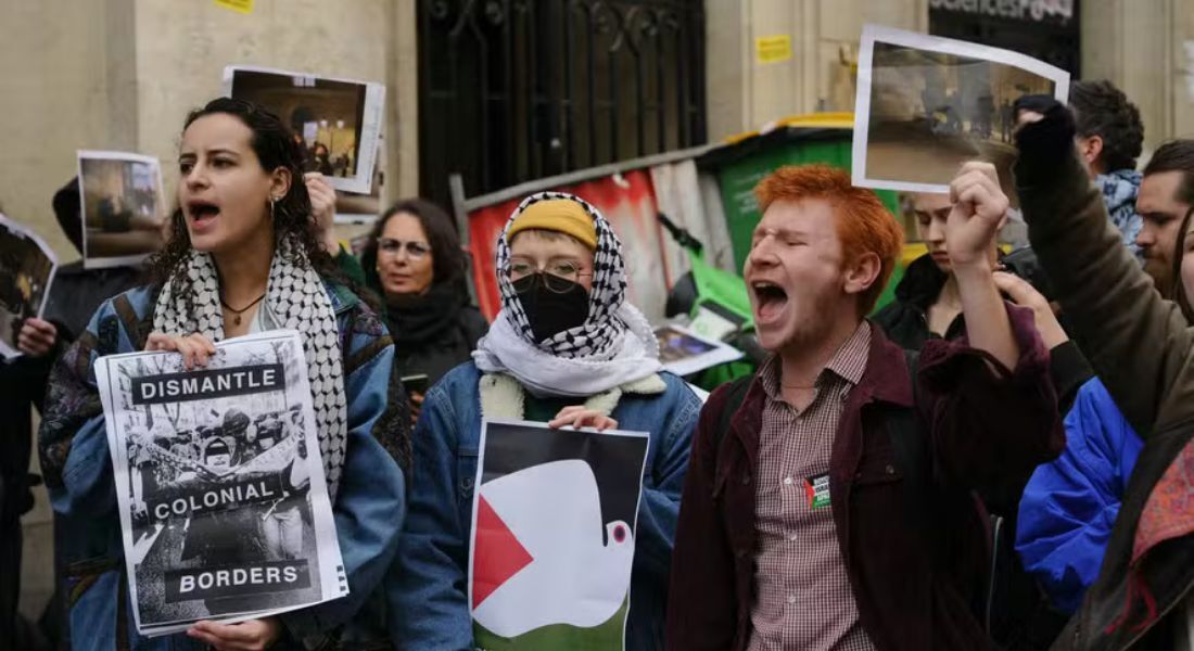 Manifestantes seguram cartazes com os dizeres 'desmantelar fronteiras coloniais' enquanto estudantes ocupam um prédio do Instituto de Estudos Políticos em apoio aos palestinos