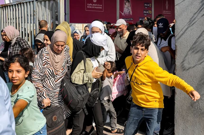 Pessoas atravessam um portão para entrar na passagem de fronteira de Rafah para o Egito, no sul da Faixa de Gaza 