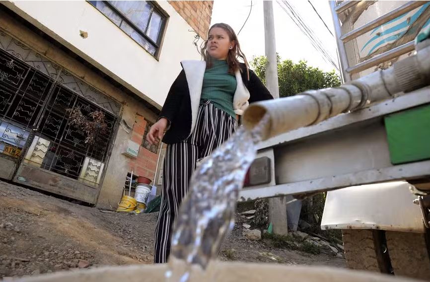 Uma mulher recolhe água potável de um caminhão pipa em La Calera, perto de Bogotá. 