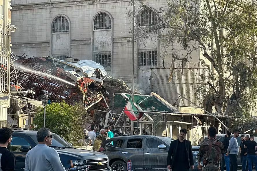 Equipes de emergência se reúnem no local dos ataques que atingiram um prédio adjacente à embaixada iraniana em Damasco, capital da Síria 