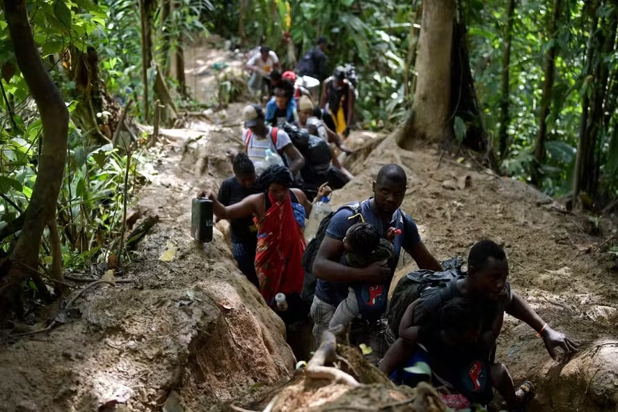 Imigrantes haitianos atravessando a trilha da selva de Darién 