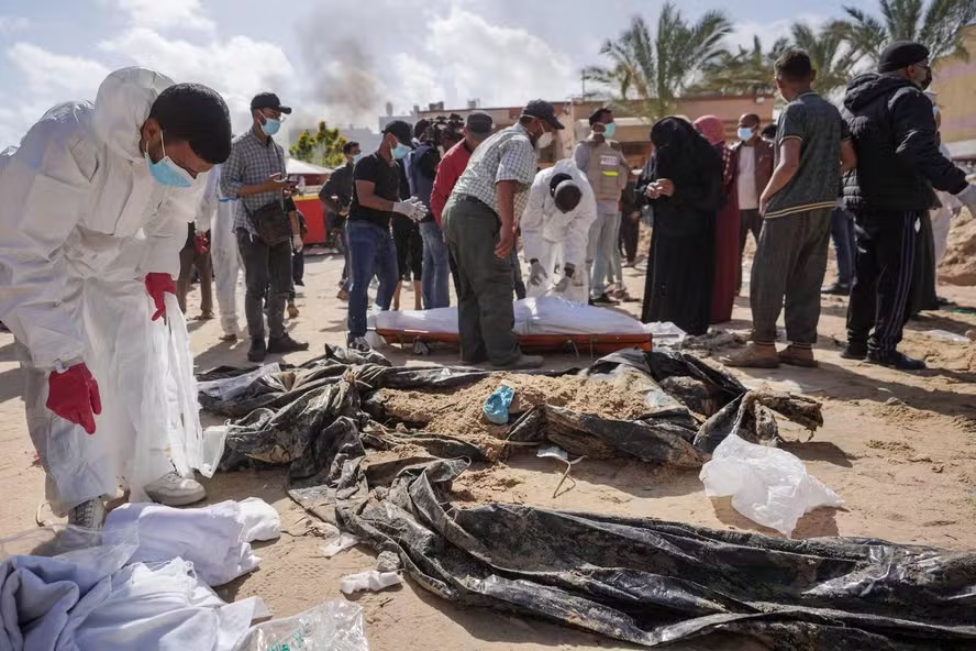 Profissionais de saúde palestinos desenterram um corpo enterrado pelas forças israelenses no complexo do hospital Nasser em Khan Yunis, no sul da Faixa de Gaza.