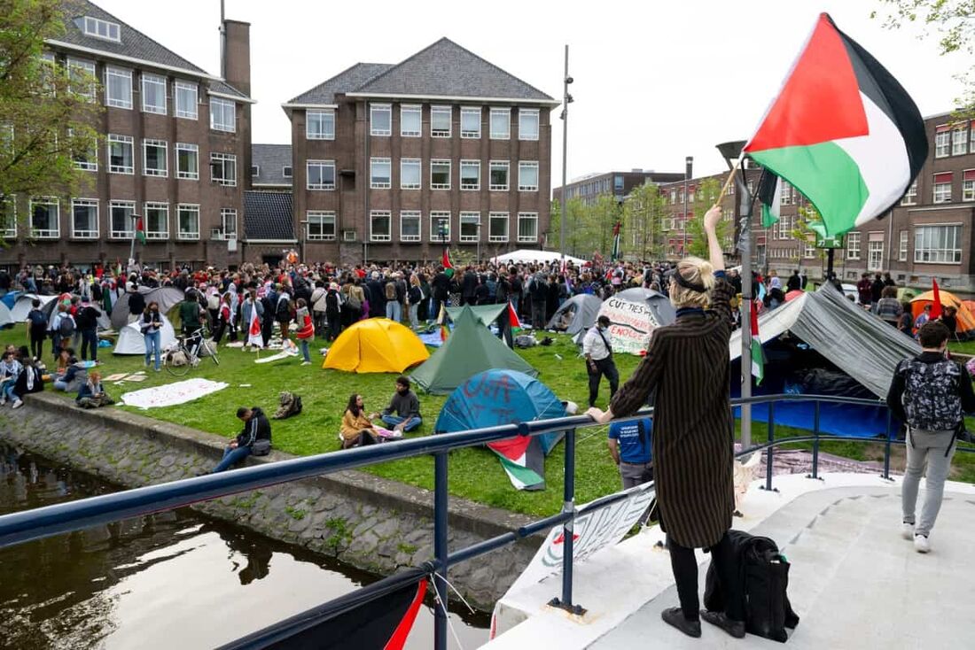 Estudantes pró-palestinos agitam bandeiras palestinas e placas enquanto ocupam o campus da Universidade de Amsterdã.