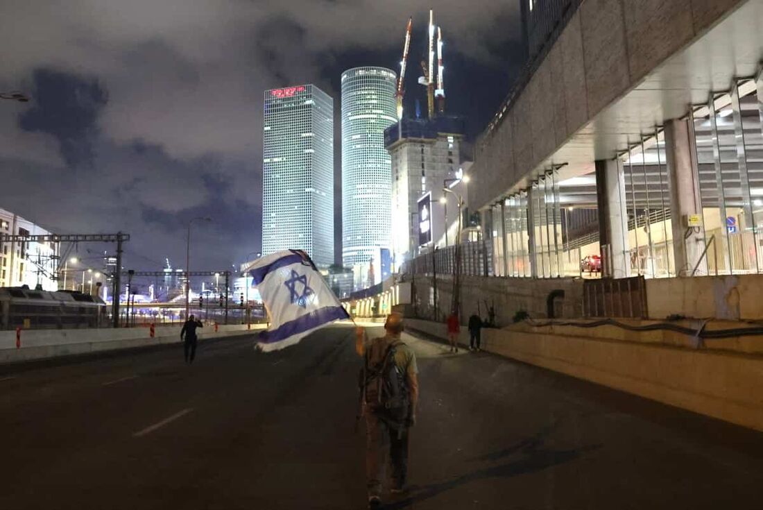 Um manifestante israelense balança a bandeira nacional.