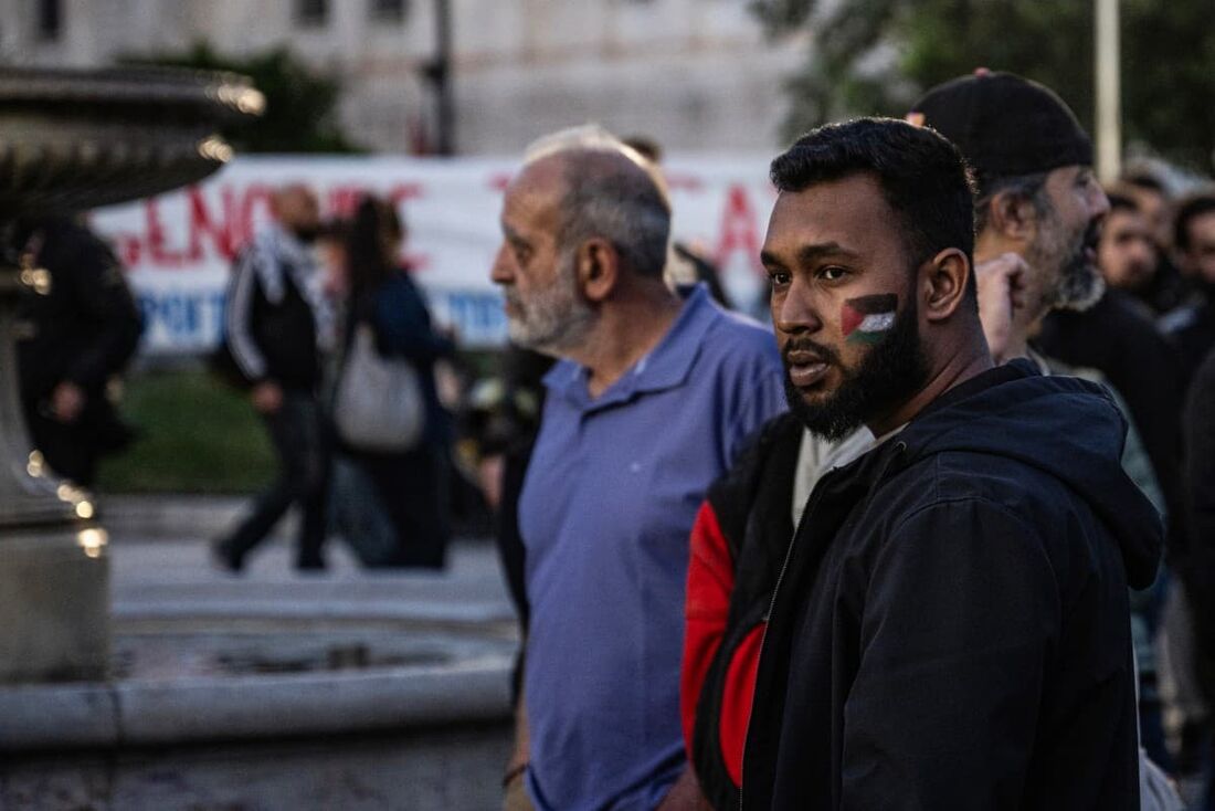 Um manifestante usando maquiagem representando uma bandeira palestina na bochecha observa enquanto estudantes e manifestantes pró-palestinos se reúnem durante uma manifestação em apoio ao povo palestino do lado de fora do prédio central da Universidade de