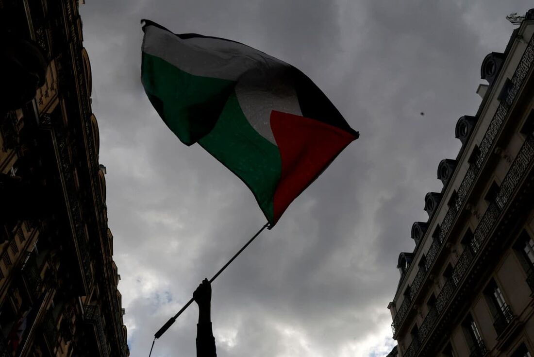 Um manifestante segura uma bandeira palestina durante uma manifestação convocada pela organização francesa