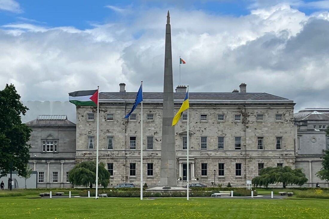 Uma bandeira palestina esq) tremula ao lado das bandeiras da UE e da Ucrânia fora de Leinster House, em Dublin